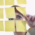 Visualize, strategize, materialize. a businesswoman arranging sticky notes on a glass wal.