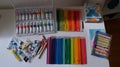 Art supplies, including paint tubes and a rainbow of colored pencils, are neatly displayed on a white table. Royalty Free Stock Photo