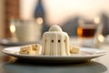 A visually appealing shot of a panna cotta dessert, with the historic Leaning Tower of Pisa gently out of focus in the backdrop.