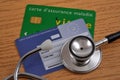 Vitale card and European health insurance card with a stethoscope on a wooden background