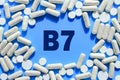 Vitamin B7 text in white capsules frame on blue background. Pill with Biotin
