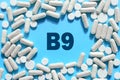 Vitamin B9 text in white capsules frame on blue background. Pill with Folate, folic acid, folacin. Dietary supplements and Royalty Free Stock Photo