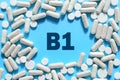 Vitamin B1 text in white capsules frame on blue background. Pill with thiamine, thiamin. Dietary supplements and medication
