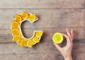 Vitamin C or Ascorbic acid nutrient in food concept. Plate in shape of letter C with orange slices and woman`s hand with citrus