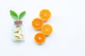 Vitamin C bottle and pills with orange fruit on white Royalty Free Stock Photo