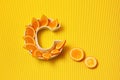 Vitamin C in food concept. Plate in shape of letter C with orange slices on bright yellow background. Ascorbic acid is important Royalty Free Stock Photo