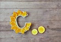 Vitamin C in food concept. Plate in shape of letter C with orange slices on wooden background. Flat lay or top view