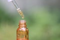 Vitamin C, Orange oil dropping to glass bottles on natural green background