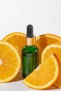 Vitamin C serum in cosmetic green bottle with dropper, sliced oranges on white background. Organic SPA cosmetics with herbal Royalty Free Stock Photo