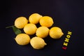 Vitamin C. Several fresh yellow lemons laying on black table near small wooden letters