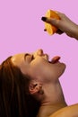 Vitamin C for skin. Delighted young pretty woman with closed eyes holding orange half over pink background Royalty Free Stock Photo