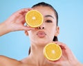 Vitamin C is vital. Studio portrait of an attractive young woman posing with two halves of an orange against a blue Royalty Free Stock Photo