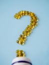 Vitamin capsules on a blue surface in the form of a question mark. Omega-3 and Vitamin D. Nutritional supplements. Yellow pills. Royalty Free Stock Photo