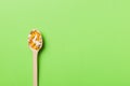 Vitamin capsules in a wooden spoon on a colored background. Pills served as a healthy meal. Drugs, pharmacy, medicine or Royalty Free Stock Photo