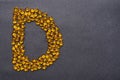 Vitamin D capsules laid out in the shape of the letter D on a black background. Health support and treatment.