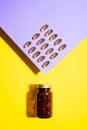 Vitamin D capsules. Omega pills in glass bottle on yellow lilac background with trendy shadows. Concept wellness, heathy lifestyle Royalty Free Stock Photo