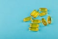 Vitamin D yellow pills on blue background. Medicine gel tablets of vitamin d on table. Yellow vitamin D oil capsule.