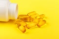 Vitamin D yellow pills on yellow background and white plastic jar. Medicine gel tablets of vitamin d on table. Yellow