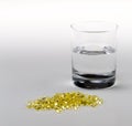 Vitamin E Pills Capsules White Background with glass of water tight close view crop