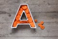 Vitamin A in food concept. Plate in the shape of the letter A with sliced fresh carrots on wooden background. Flat lay. Royalty Free Stock Photo