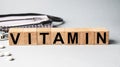 VITAMIN inscription on wooden cubes isolated on white background, medicine concept. Nearby on the table are a stethoscope and Royalty Free Stock Photo