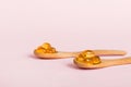 Vitamin omega capsules in a spoon on a colored background. Pills served as a healthy meal. Red soft gel vitamin