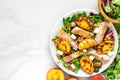 Vitamin salad with grilled chicken and peach, feta cheese and walnuts in a plate. healthy food. top view Royalty Free Stock Photo