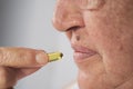 Vitamin And Supplement. Closeup Of Beautiful Old Woman Taking Yellow Fish Oil Pill Royalty Free Stock Photo