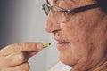 Vitamin And Supplement. Closeup Of Beautiful Old Woman Taking Yellow Fish Oil Pill Royalty Free Stock Photo