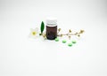 Vitamin and supplement tablet pills with flower and branch and blank label amber glass bottle on white background with copy space, Royalty Free Stock Photo