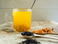 Vitaminic healthy sea buckthorn tea in small cup with fresh raw sea buckthorn berries and black tea in wooden spoons Royalty Free Stock Photo