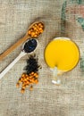 Vitaminic healthy sea buckthorn tea in small cup with fresh raw sea buckthorn berries and black tea in wooden spoons Royalty Free Stock Photo