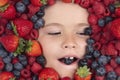 Vitamins from berrie. Berries mix blueberry, raspberry, strawberry, blackberry. Child face with berry frame, close up. Royalty Free Stock Photo