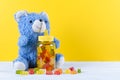 Vitamins for children like jelly candy and teddy bear on yellow background