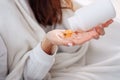 Vitamins and food supplements concept. Female hand pouring yellow pills out of bottle into palm. Woman spilling out