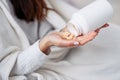 Vitamins and food supplements concept. Female hand pouring beige pills out of bottle into palm. Woman spilling out