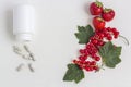 Vitamins supplements as a capsule with fresh berries from the medicine jar on white background Royalty Free Stock Photo