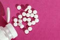 Vitamins in white pills pouring out of white plastic bottle on pink background with copy space Royalty Free Stock Photo