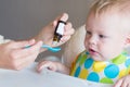 Vitamins for young children. mom drips vitamins into a spoon while feeding her little son. healthy childhood