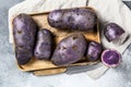 Vitelotte raw potato on a chopping Board. Gray background. Top view Royalty Free Stock Photo