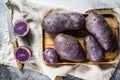 Vitelotte raw potato on a chopping  Board. Gray background. Top view. Space for text Royalty Free Stock Photo