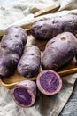 Vitelotte raw potato on a  chopping Board. Gray background. Top view Royalty Free Stock Photo