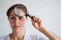 Vitiligo. Portrait of a beautiful woman with lack of skin pigmentation on her forehead with a magnifier in her hands. A