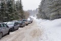 Winter road in the forest and long line of parked vehicles