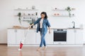 Asian lady using upright vacuum with music in headphones