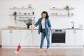 Asian lady using upright vacuum with music in headphones