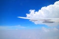 Blue sky and pure white clouds with airplane wing seen from plane window during flight Royalty Free Stock Photo