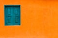 Vivid bright orange colour facade with blue-green window and large empty orange wall texture