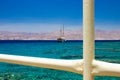 Vivid colorful port south scenic view white industrial fence foreground frame work and cruise ship on Red sea aquamarine waters