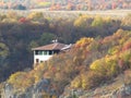 Vivid colourful yellow autumn fall season. Small cottage house in mountains on the rocks surrounded by trees,  shrubs and bushes. Royalty Free Stock Photo